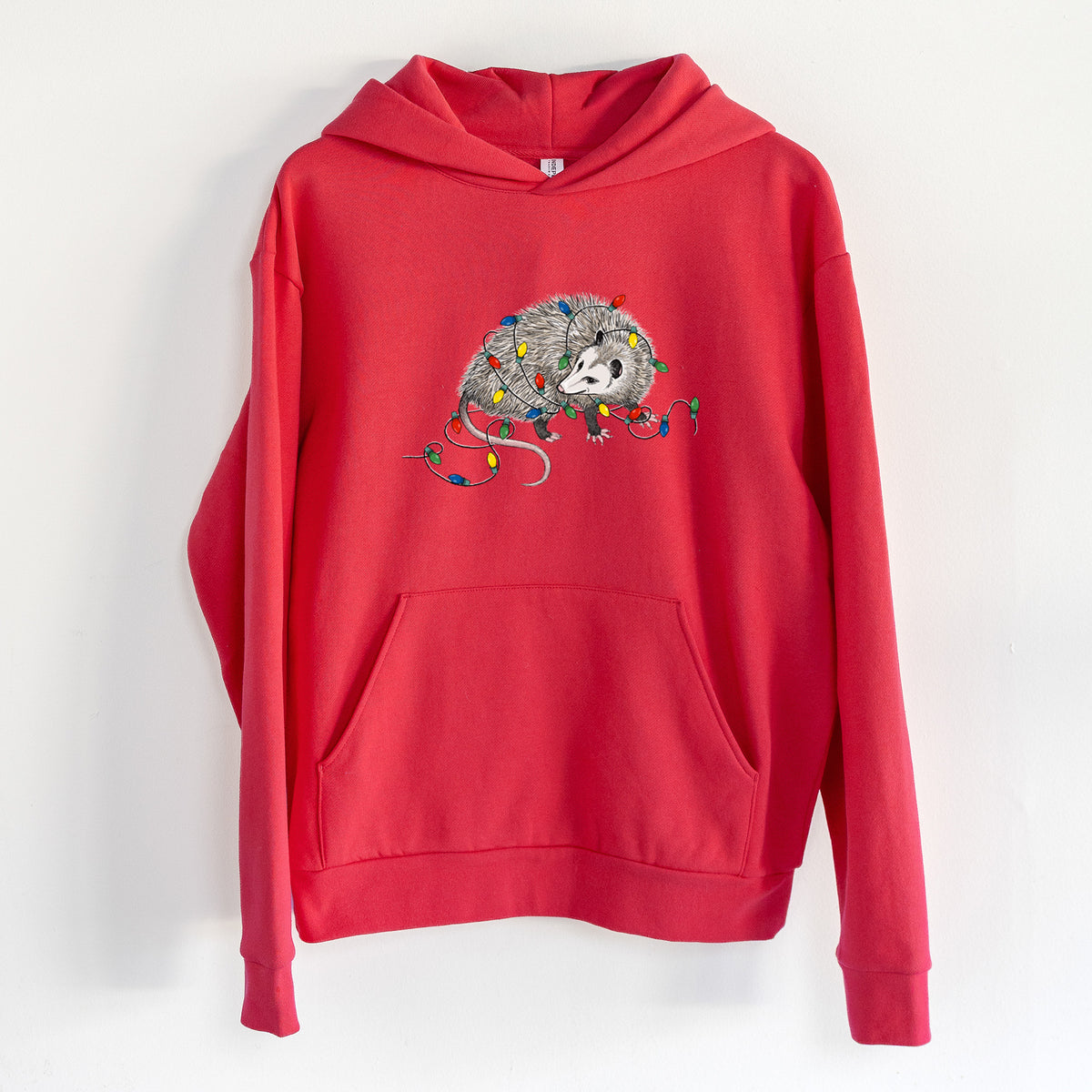 Christmas Opossum - Statement Midweight Hoodie in Cherry Red, hanging on a white wall, with a front kangaroo pocket and no drawcords.