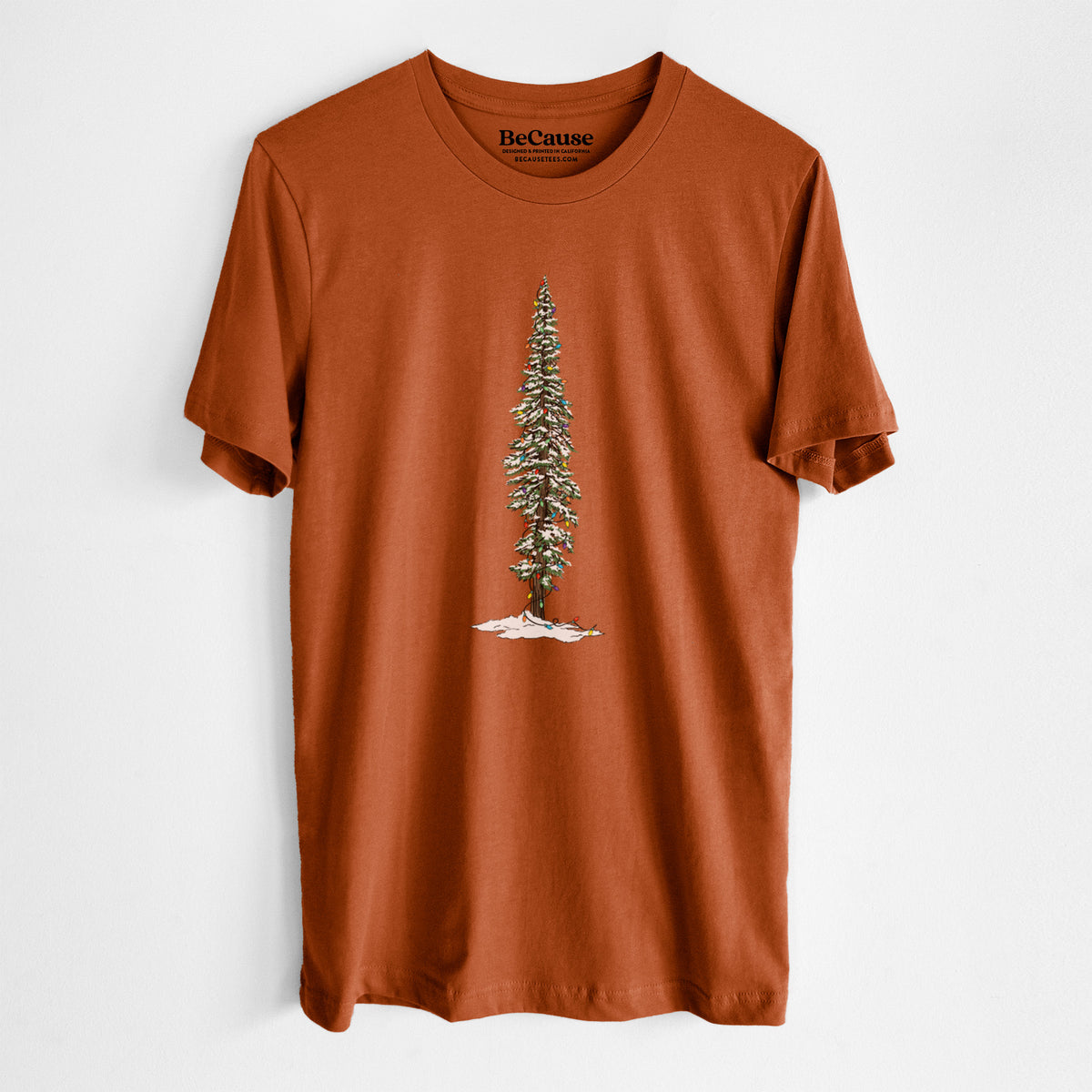 Autumn lightweight cotton t-shirt laid flat, printed with a full-color illustration of a tall redwood tree dusted with snow and strung with holiday lights.