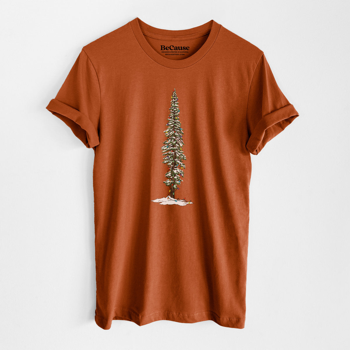 Autumn lightweight cotton t-shirt laid flat, printed with a full-color illustration of a tall redwood tree dusted with snow and strung with holiday lights.