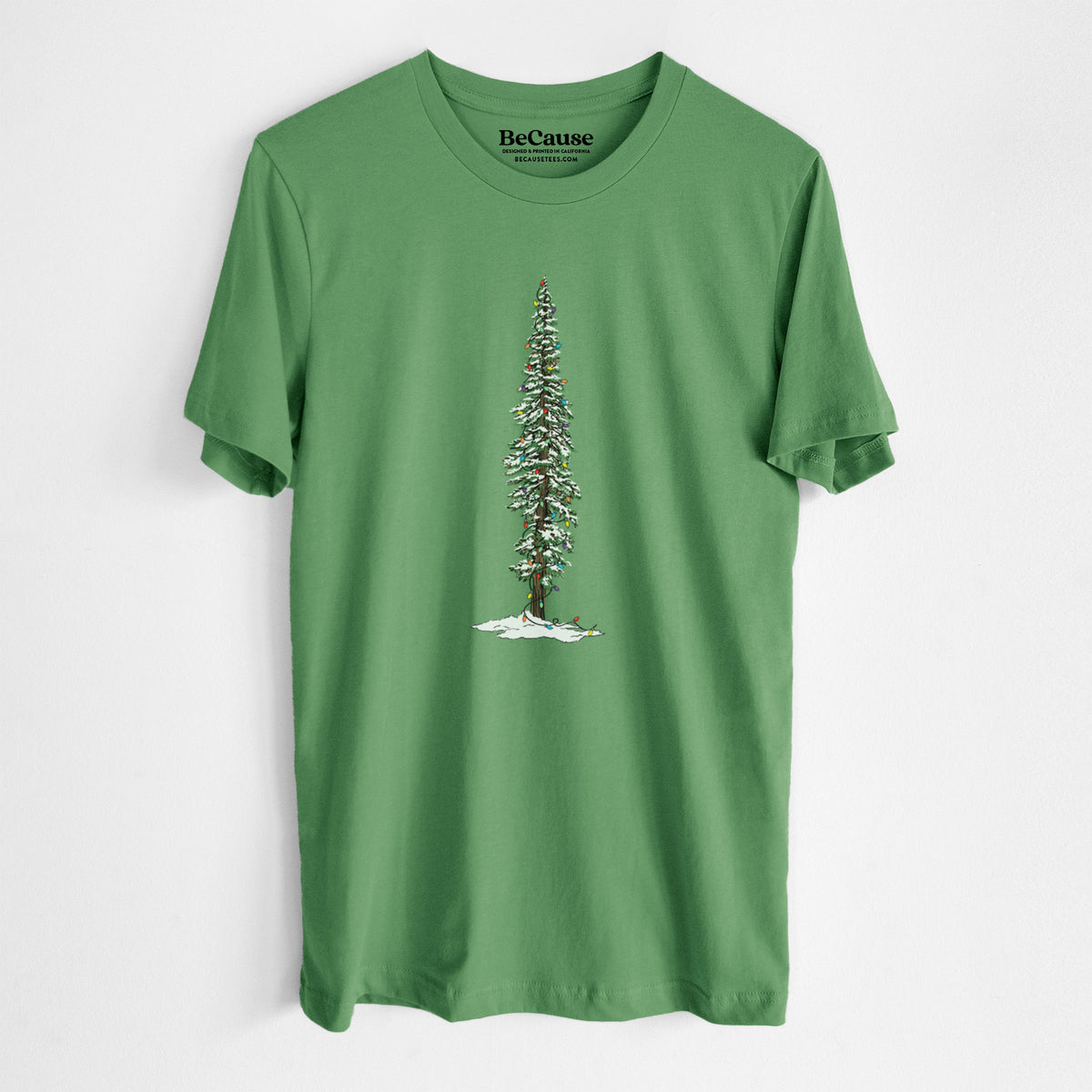 Leaf green lightweight cotton t-shirt laid flat, printed with a full-color illustration of a tall redwood tree dusted with snow and strung with holiday lights.