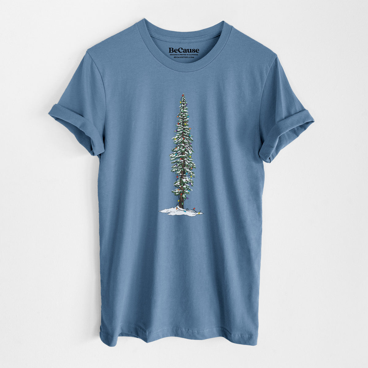 Steel blue lightweight cotton t-shirt laid flat, printed with a full-color illustration of a tall redwood tree dusted with snow and strung with holiday lights.