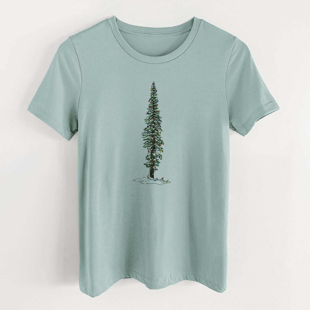 Dusty blue women's relaxed fit cotton t-shirt laid flat, printed with a full-color illustration of a tall redwood tree dusted with snow and strung with holiday lights.