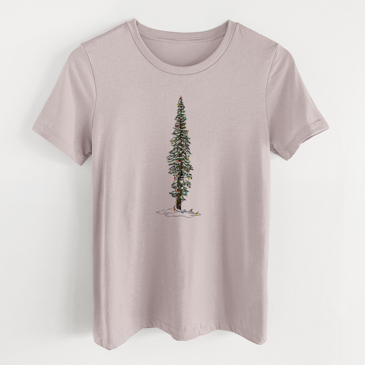 Pink gravel women's relaxed fit cotton t-shirt laid flat, printed with a full-color illustration of a tall redwood tree dusted with snow and strung with holiday lights.