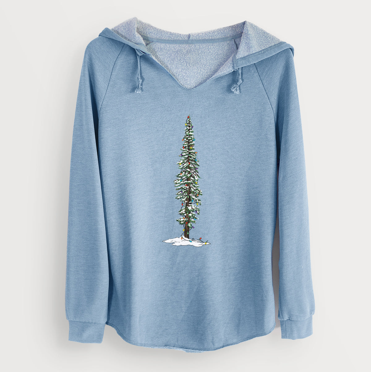 Misty blue women's Cali Wave hooded sweatshirt laid flat, printed with a full-color illustration of a tall redwood tree dusted with snow and strung with holiday lights.