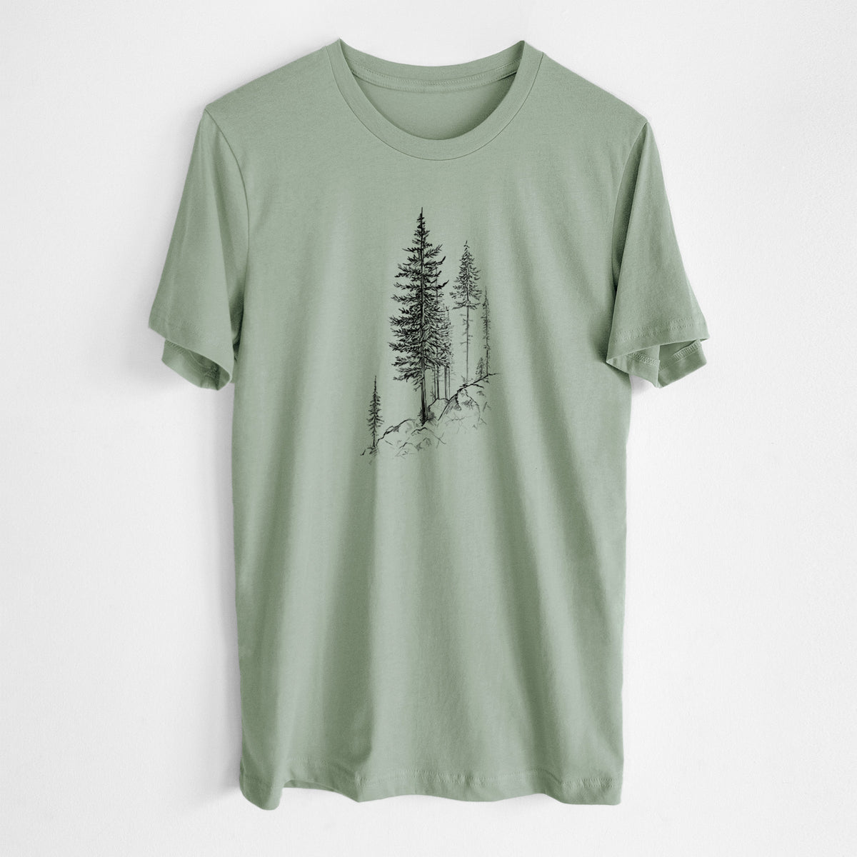Sage green lightweight cotton t-shirt laid flat, printed with a black ink illustration of tall pine trees growing from a rocky cliff.
