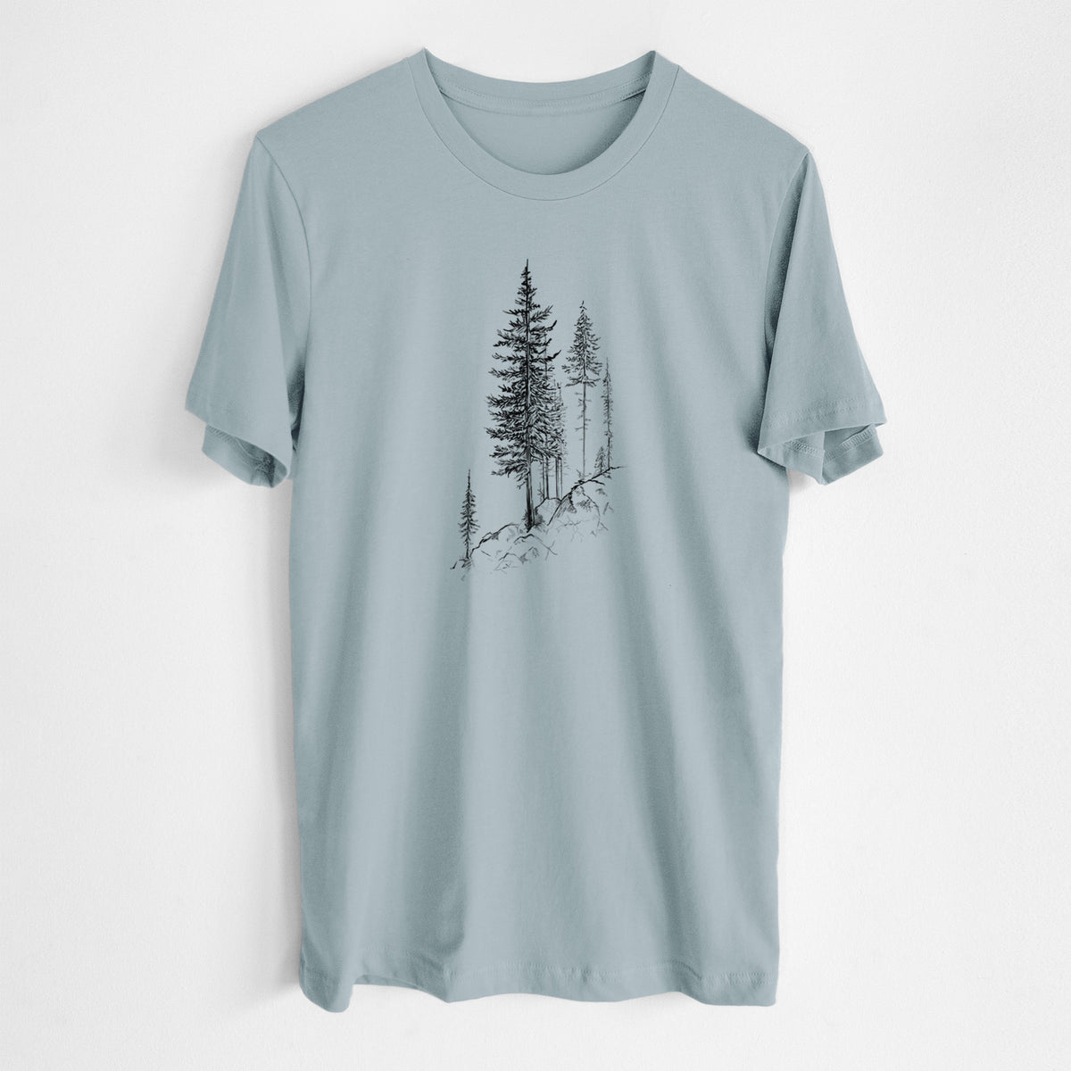 Vintage denim lightweight cotton t-shirt laid flat, printed with a black ink illustration of tall pine trees growing from a rocky cliff.