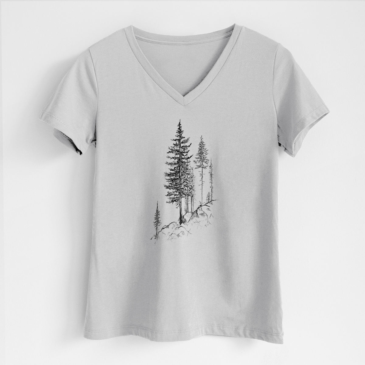 Lunar grey women's relaxed fit cotton V-neck t-shirt laid flat, printed with a black ink illustration of tall pine trees growing from a rocky cliff.