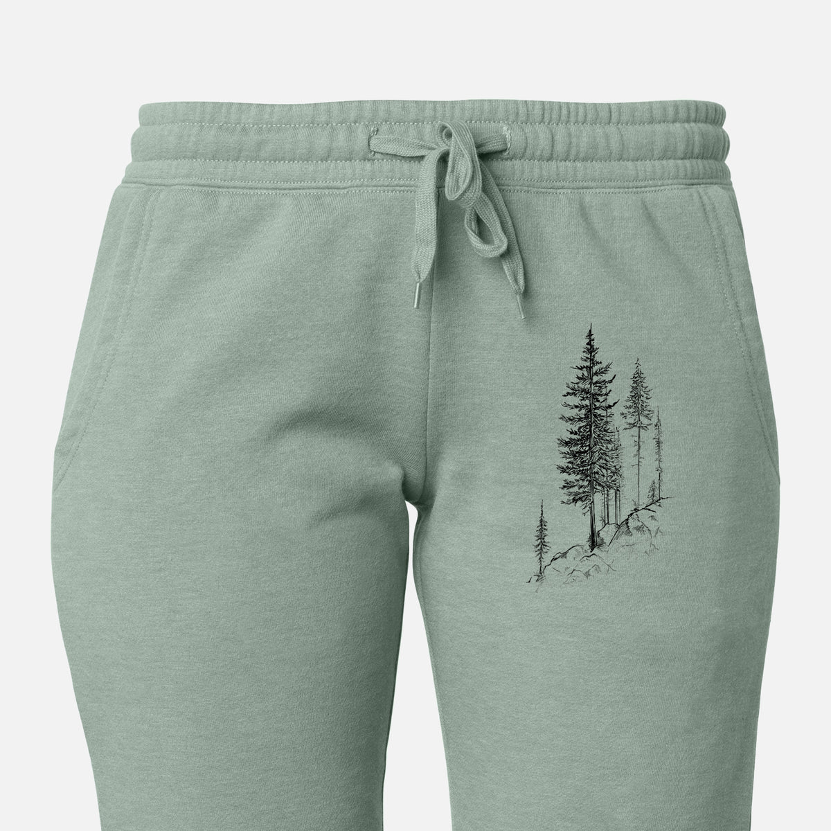 Front of sage green Cali Wave sweatpants, printed with a black ink illustration of tall pine trees growing from a rocky cliff on the leg.