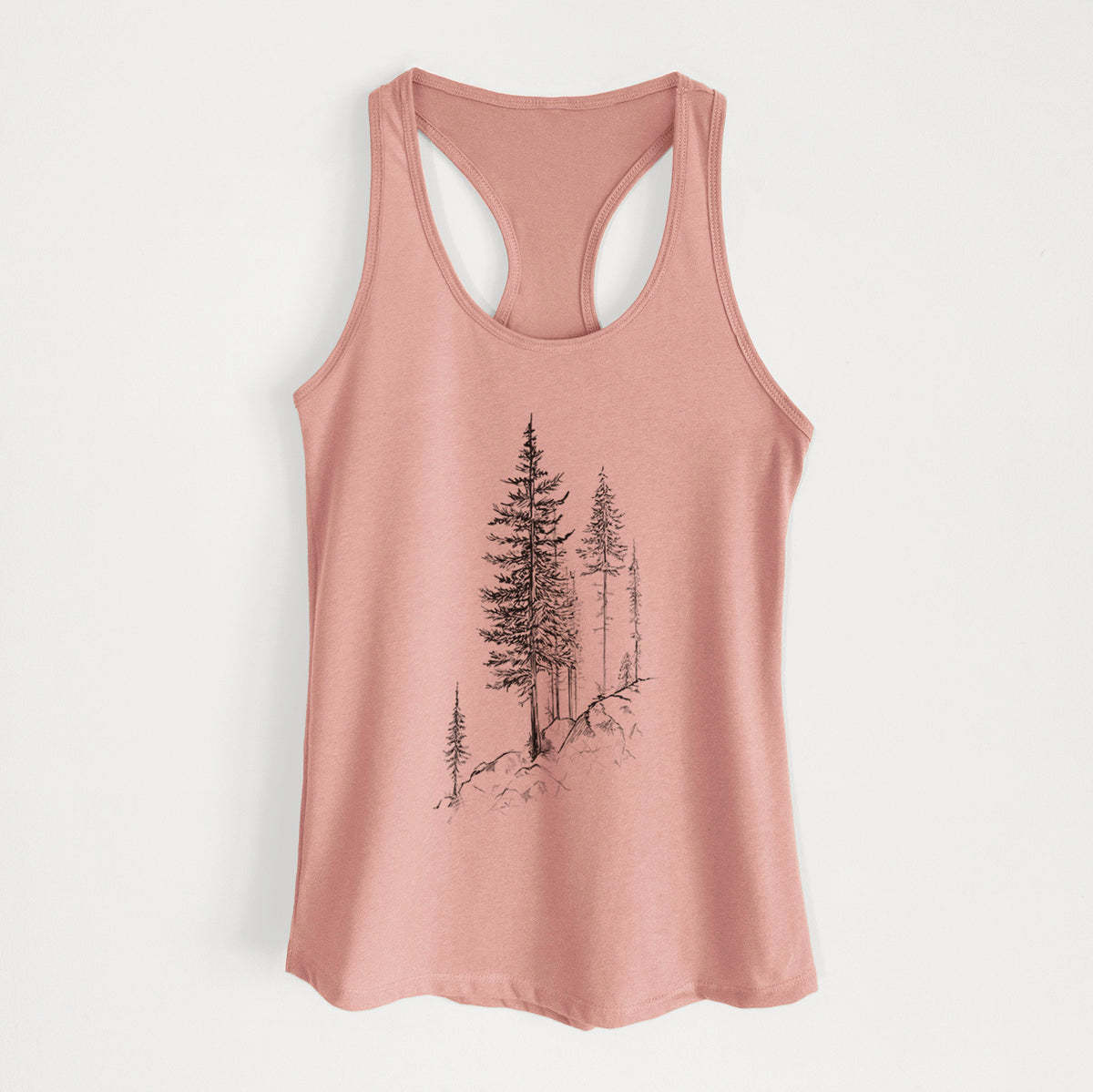 Desert pink women's racerback tank top laid flat, printed with a black ink illustration of tall pine trees growing from a rocky cliff.