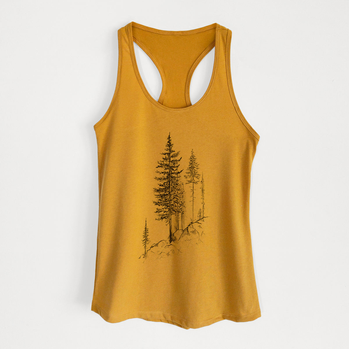 Gold women's racerback tank top laid flat, printed with a black ink illustration of tall pine trees growing from a rocky cliff.