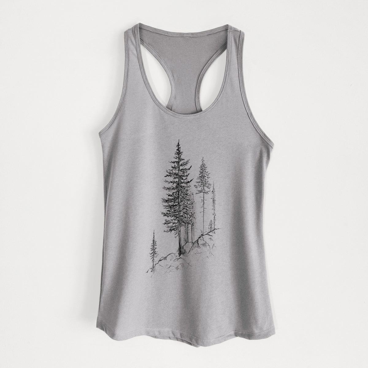 Heather grey women's racerback tank top laid flat, printed with a black ink illustration of tall pine trees growing from a rocky cliff.