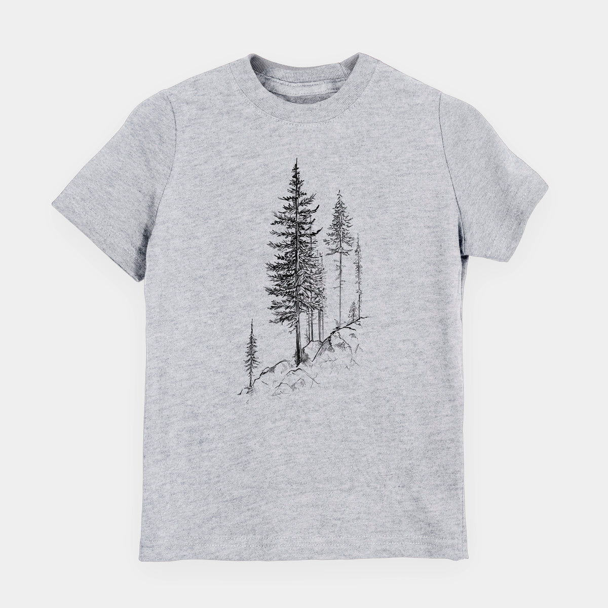 Heather grey youth t-shirt laid flat, printed with a black ink illustration of tall pine trees growing from a rocky cliff.