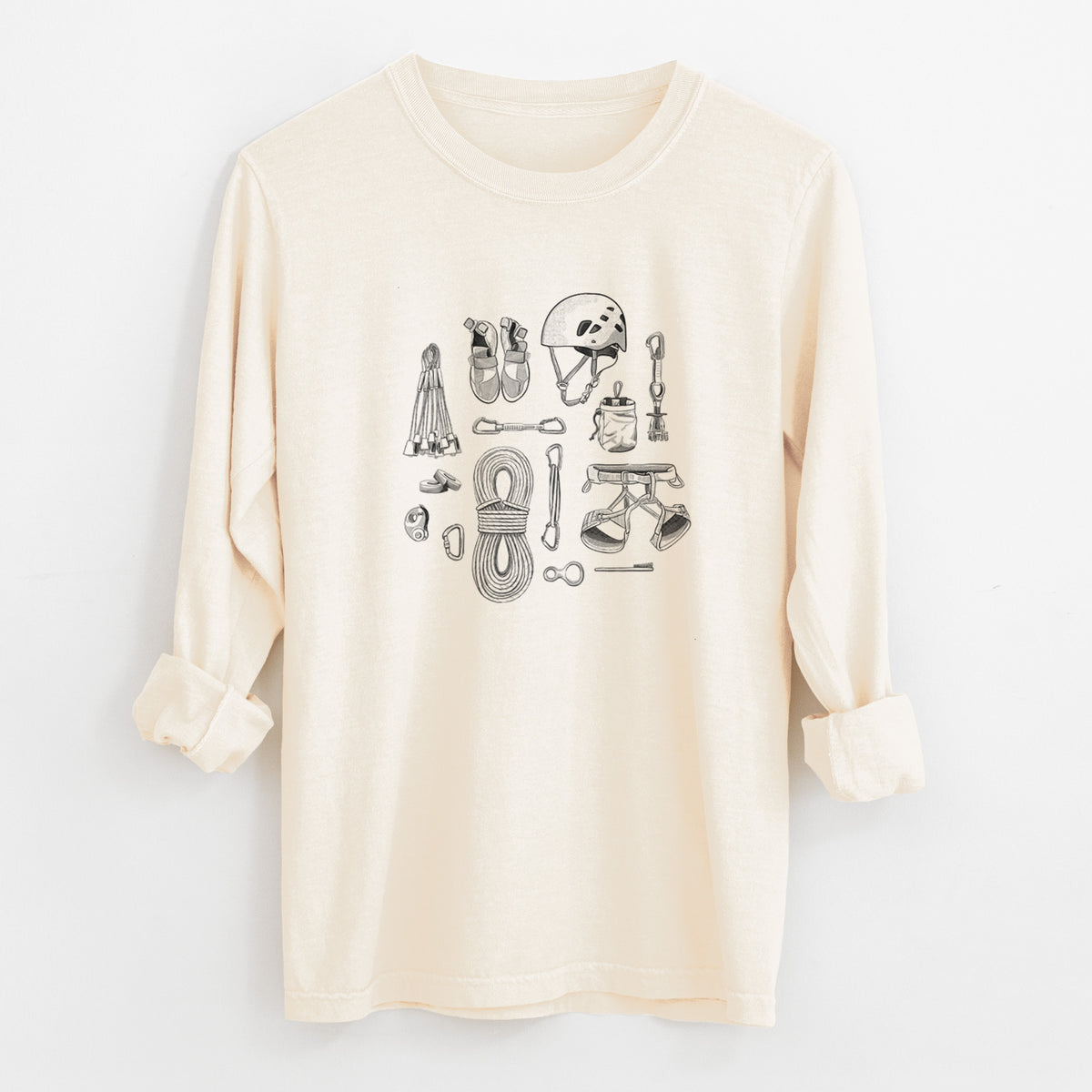 Ivory Comfort Colors long sleeve shirt laid flat with the cuffs rolled, printed with a black ink flat lay of rock climbing gear, including a helmet, shoes, rope, harness and carabiners.