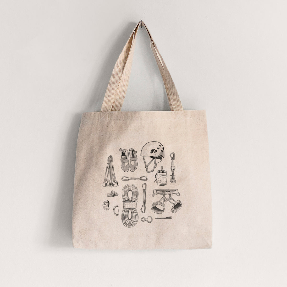 Natural canvas tote bag printed with a black ink flat lay of rock climbing gear, including a helmet, shoes, rope, harness and carabiners.