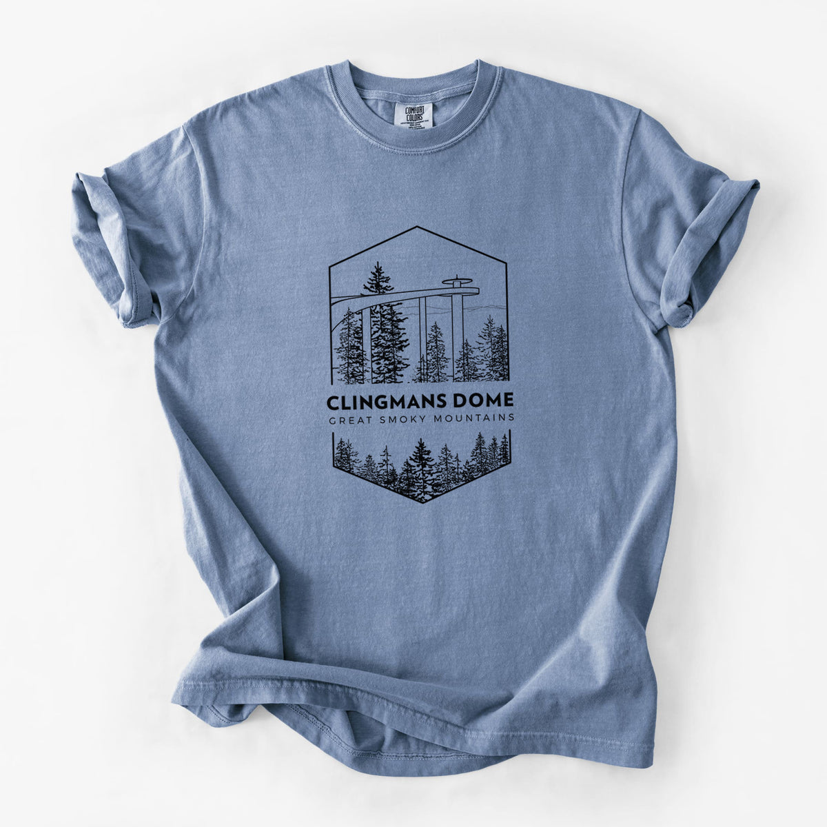 Blue jean Comfort Colors t-shirt laid flat, printed with a black line art badge of the Clingmans Dome observation tower above a pine forest, with the words Clingmans Dome, Great Smoky Mountains.