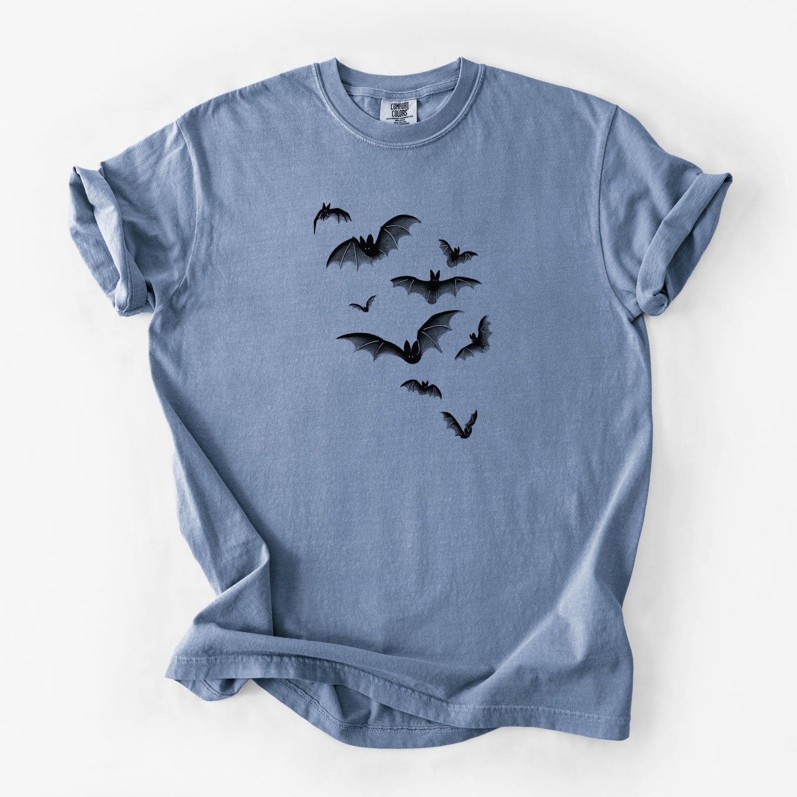 Blue jean Comfort Colors t-shirt laid flat, printed with a black ink illustration of a cloud of bats in flight.