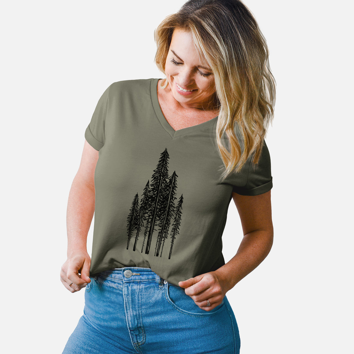 Woman wearing a military green women's relaxed fit cotton V-neck t-shirt printed with a black ink illustration of a stand of tall coastal redwood trees with slender trunks and layered branches.