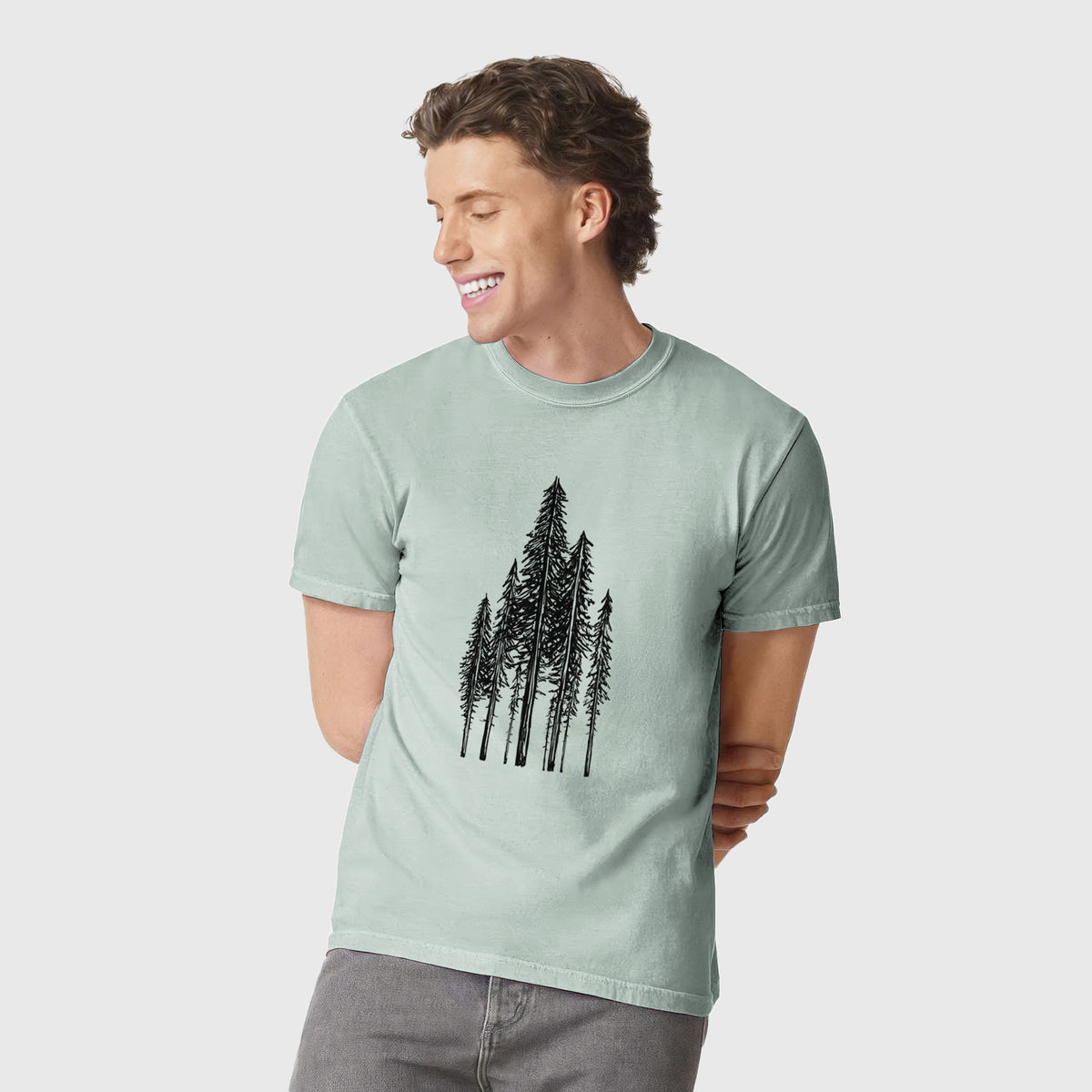 Man wearing a Comfort Colors t-shirt printed with a black ink illustration of a stand of tall coastal redwood trees with slender trunks and layered branches.