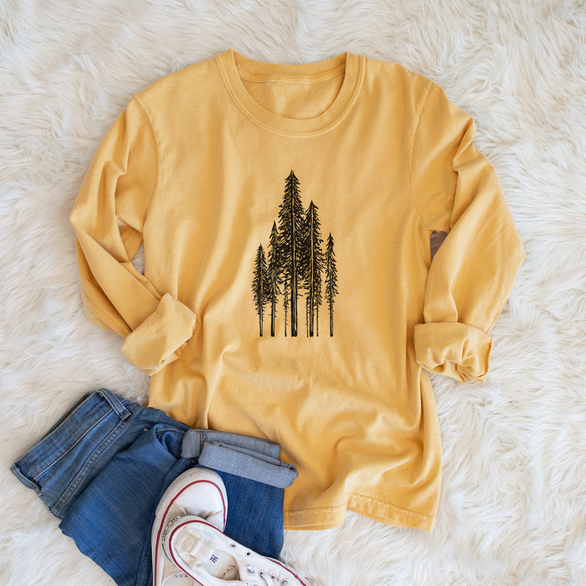 Golden wheat yellow Comfort Colors long sleeve shirt printed with a black ink illustration of a stand of tall coastal redwood trees with slender trunks and layered branches, shown in a lifestyle photo.