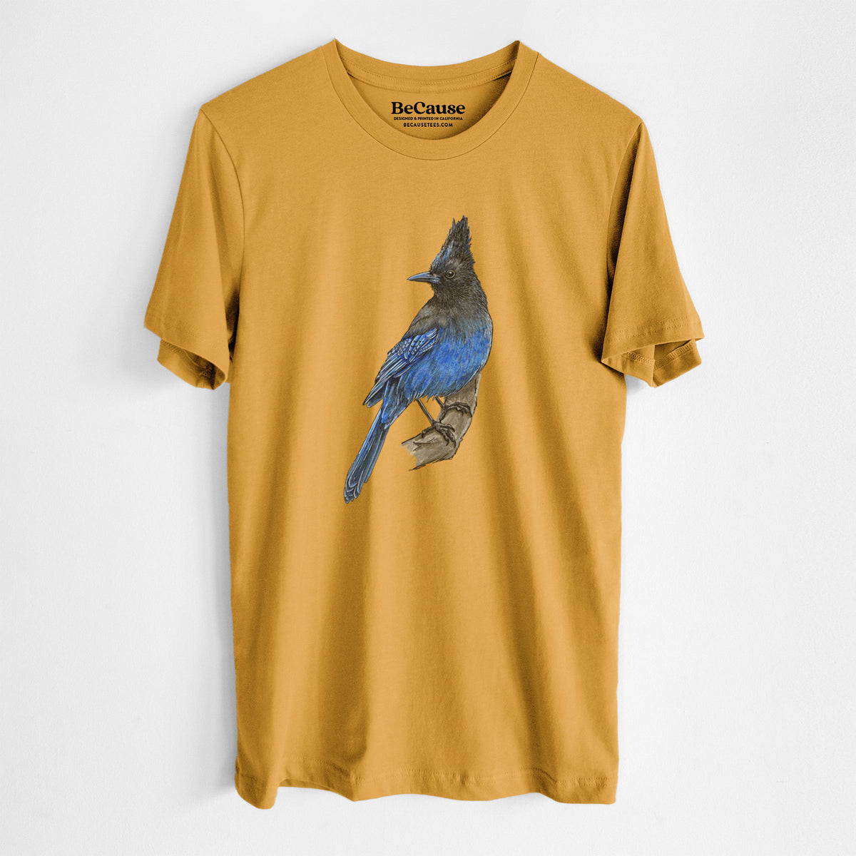 Mustard yellow lightweight cotton t-shirt laid flat, printed with a full-color illustration of a Steller's jay perched with its dark crest raised.