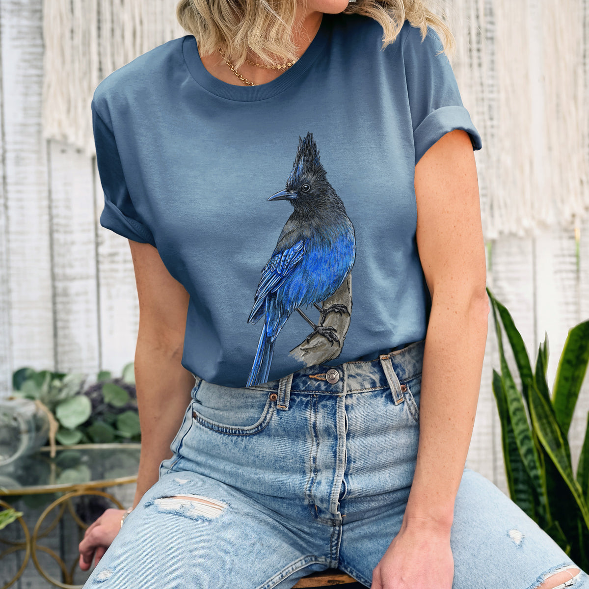Woman wearing a steel blue lightweight cotton t-shirt printed with a full-color illustration of a Steller's jay perched with its dark crest raised.