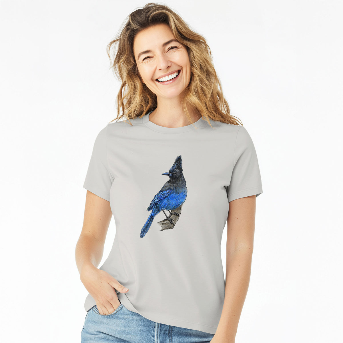 Woman wearing a lunar grey women's relaxed fit cotton t-shirt printed with a full-color illustration of a Steller's jay perched with its dark crest raised.