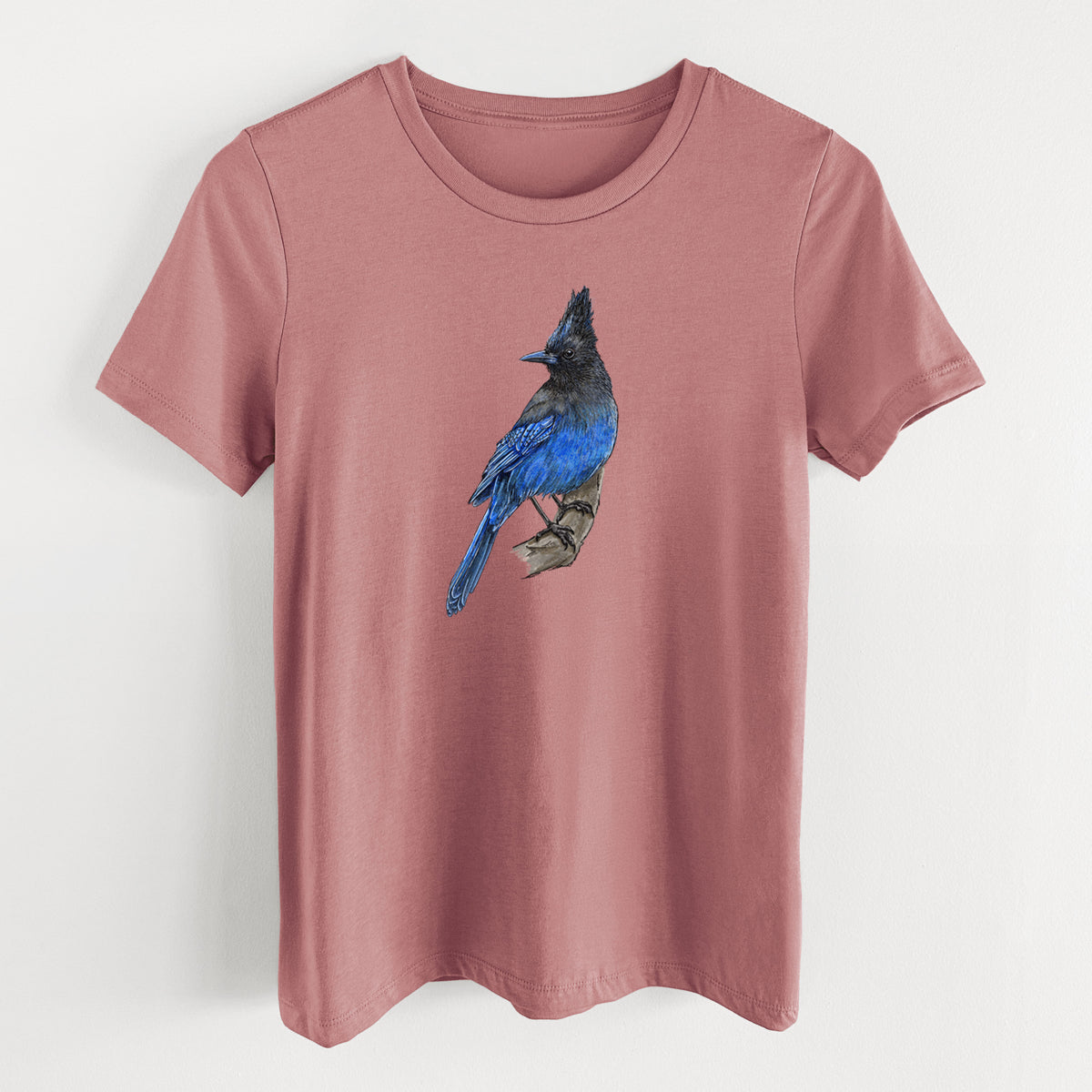 Mauve pink women's relaxed fit cotton t-shirt laid flat, printed with a full-color illustration of a Steller's jay perched with its dark crest raised.
