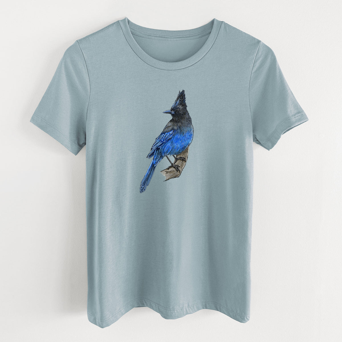 Vintage denim women's relaxed fit cotton t-shirt laid flat, printed with a full-color illustration of a Steller's jay perched with its dark crest raised.