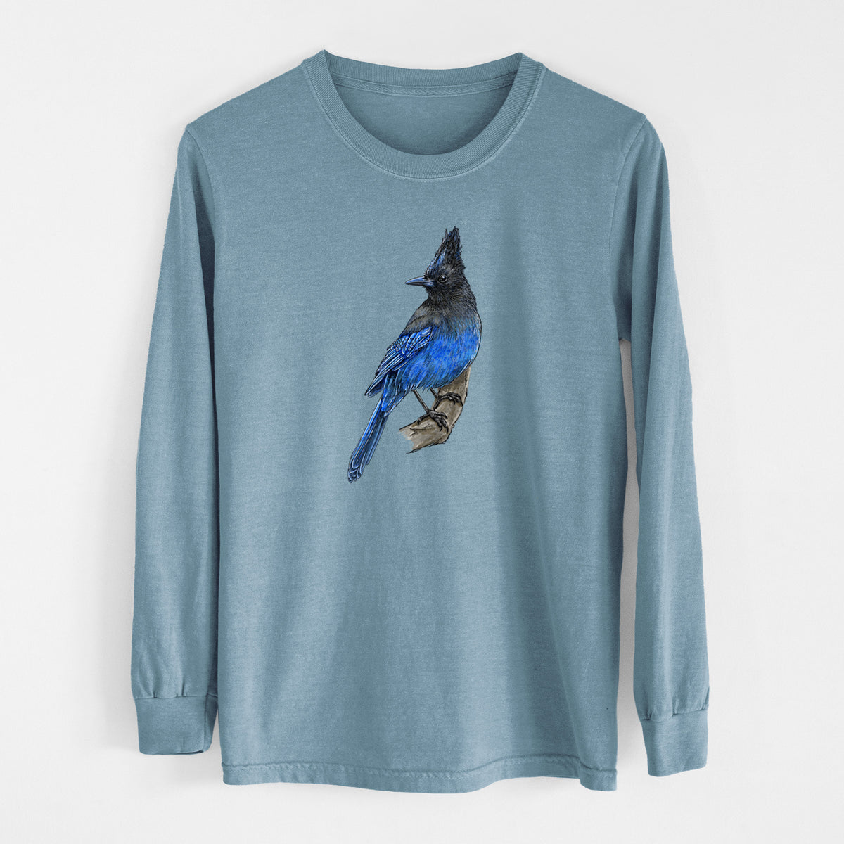 Steel blue Comfort Colors long sleeve shirt laid flat, printed with a full-color illustration of a Steller's jay perched with its dark crest raised.