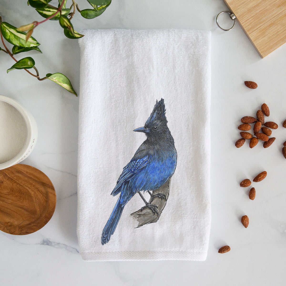White hand towel printed with a full-color illustration of a Steller's jay perched with its dark crest raised.