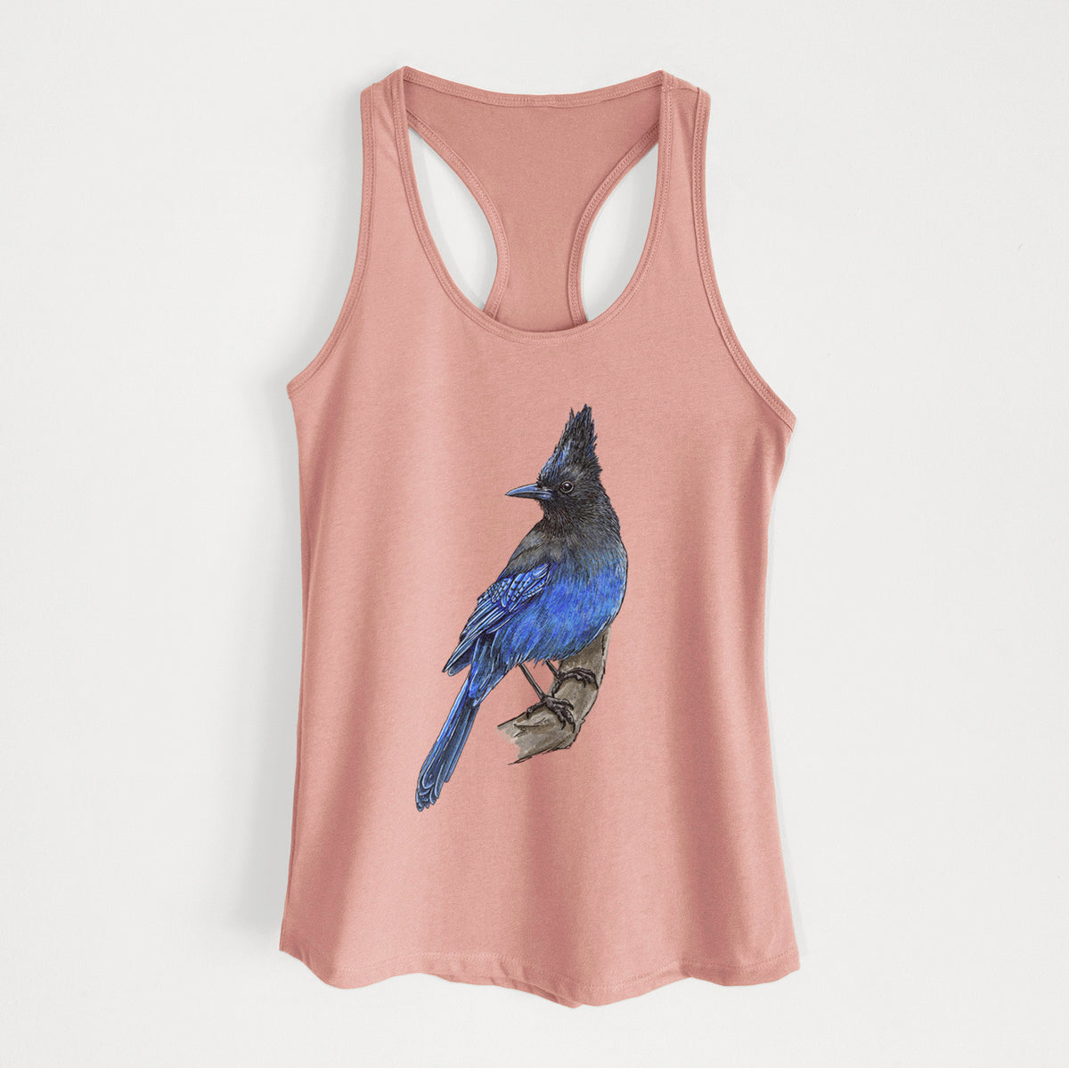 Desert pink women's racerback tank top laid flat, printed with a full-color illustration of a Steller's jay perched with its dark crest raised.