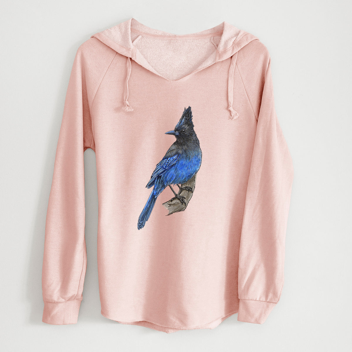 Blush pink women's Cali Wave hooded sweatshirt laid flat, printed with a full-color illustration of a Steller's jay perched with its dark crest raised.