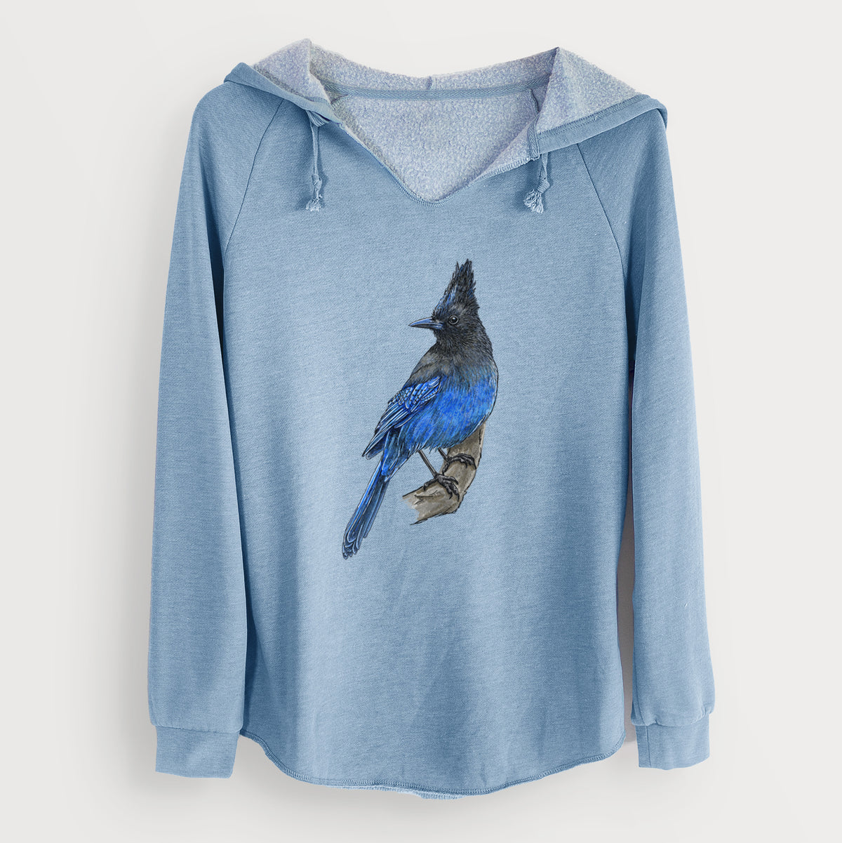Misty blue women's Cali Wave hooded sweatshirt laid flat, printed with a full-color illustration of a Steller's jay perched with its dark crest raised.