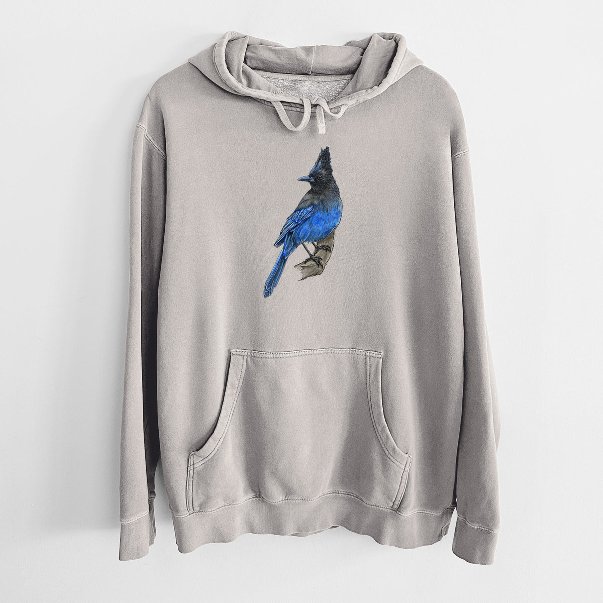 Cement grey pigment dyed hoodie laid flat, printed with a full-color illustration of a Steller's jay perched with its dark crest raised.