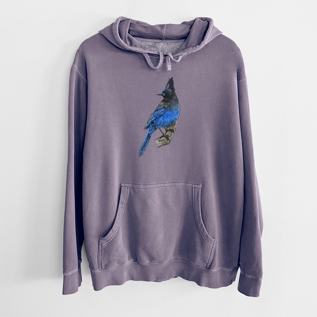Plum purple pigment dyed hoodie laid flat, printed with a full-color illustration of a Steller's jay perched with its dark crest raised.