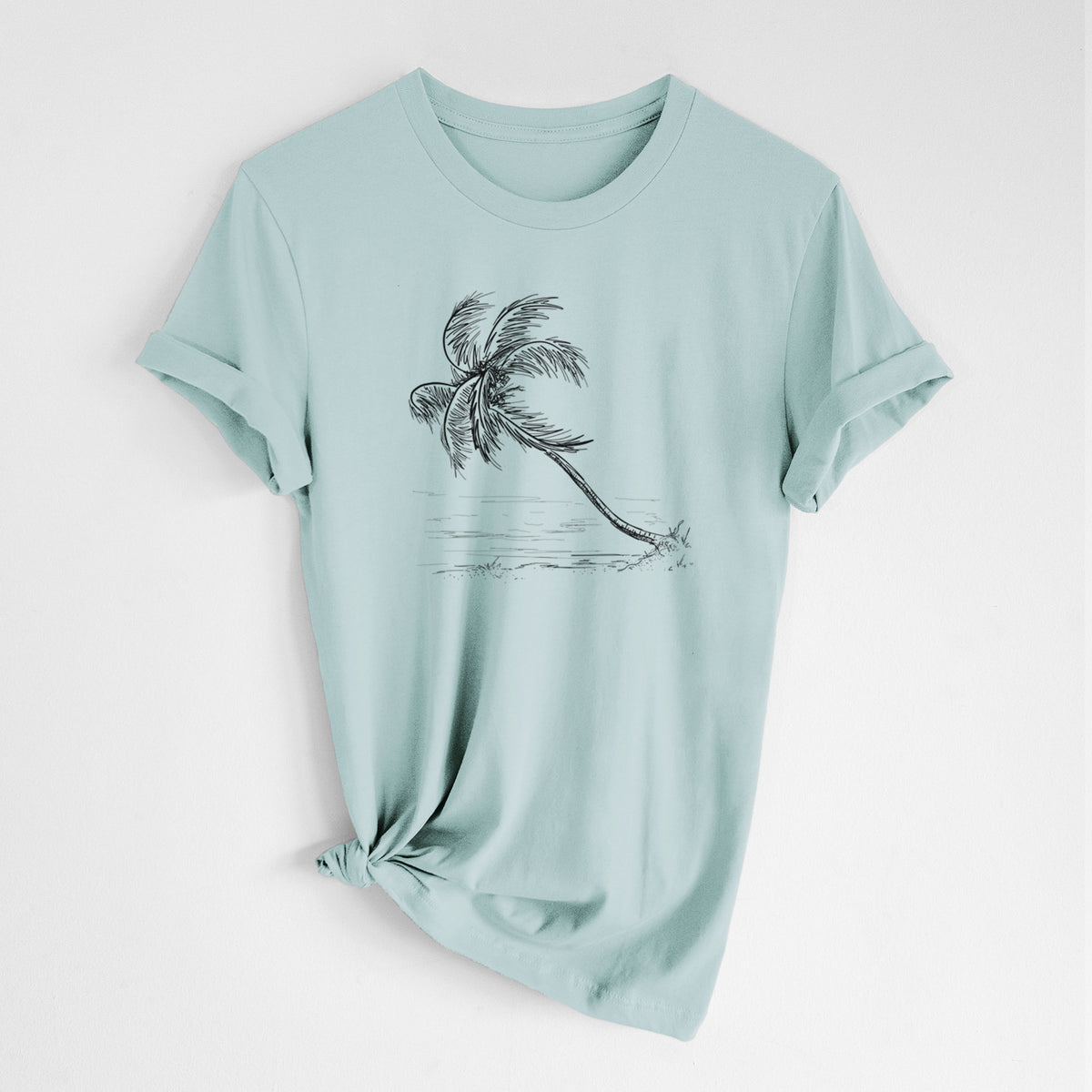 Dusty blue lightweight cotton t-shirt laid flat with the sleeves rolled, printed with a black ink illustration of a coconut palm leaning over a sandy beach.