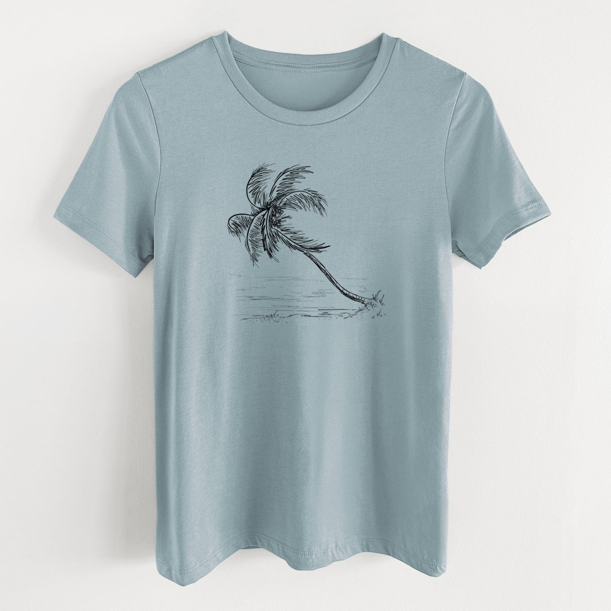 Vintage denim women's relaxed fit cotton t-shirt laid flat, printed with a black ink illustration of a coconut palm leaning over a sandy beach.