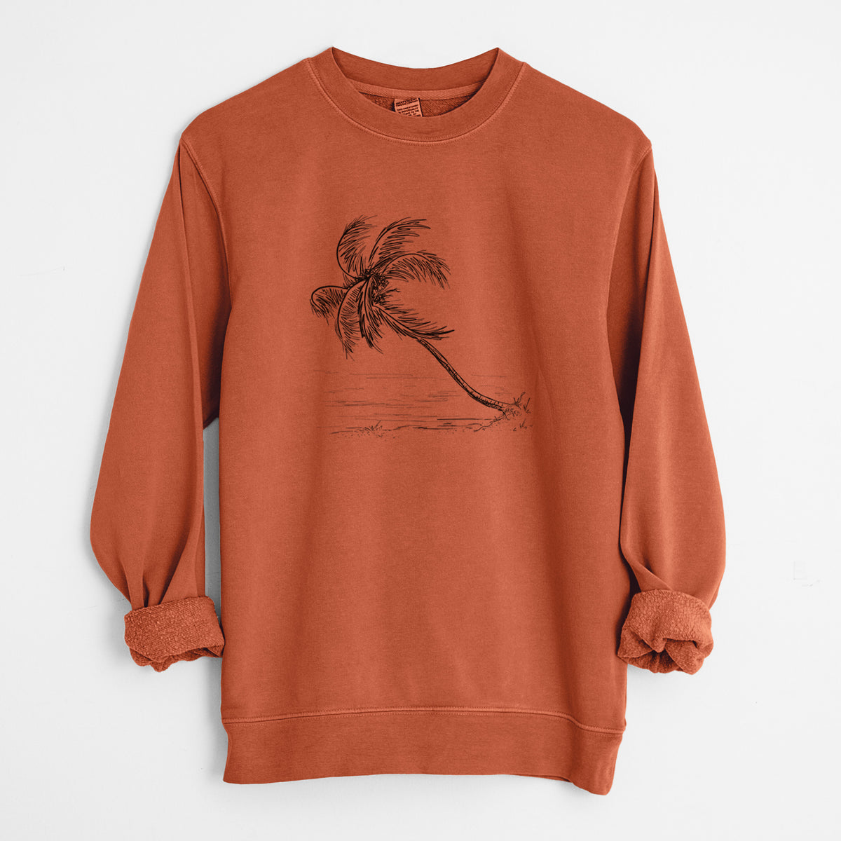 Amber orange pigment dyed crewneck sweatshirt laid flat with the sleeves rolled, printed with a black ink illustration of a coconut palm leaning over a sandy beach.