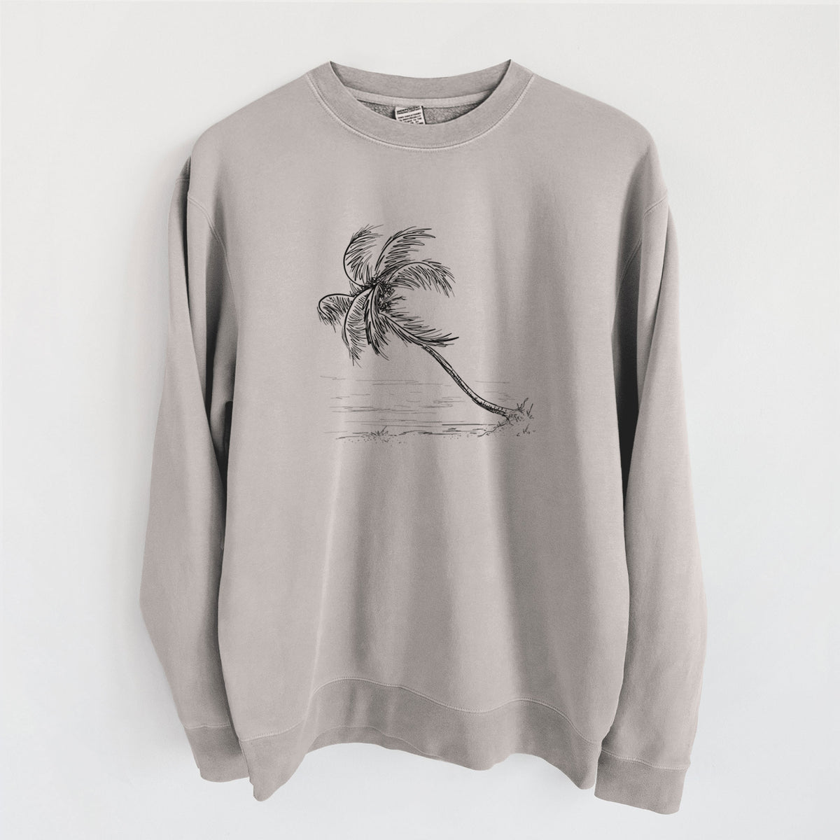Cement grey pigment dyed crewneck sweatshirt laid flat, printed with a black ink illustration of a coconut palm leaning over a sandy beach.