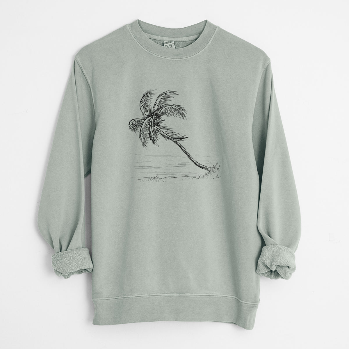 Sage green pigment dyed crewneck sweatshirt laid flat with the sleeves rolled, printed with a black ink illustration of a coconut palm leaning over a sandy beach.