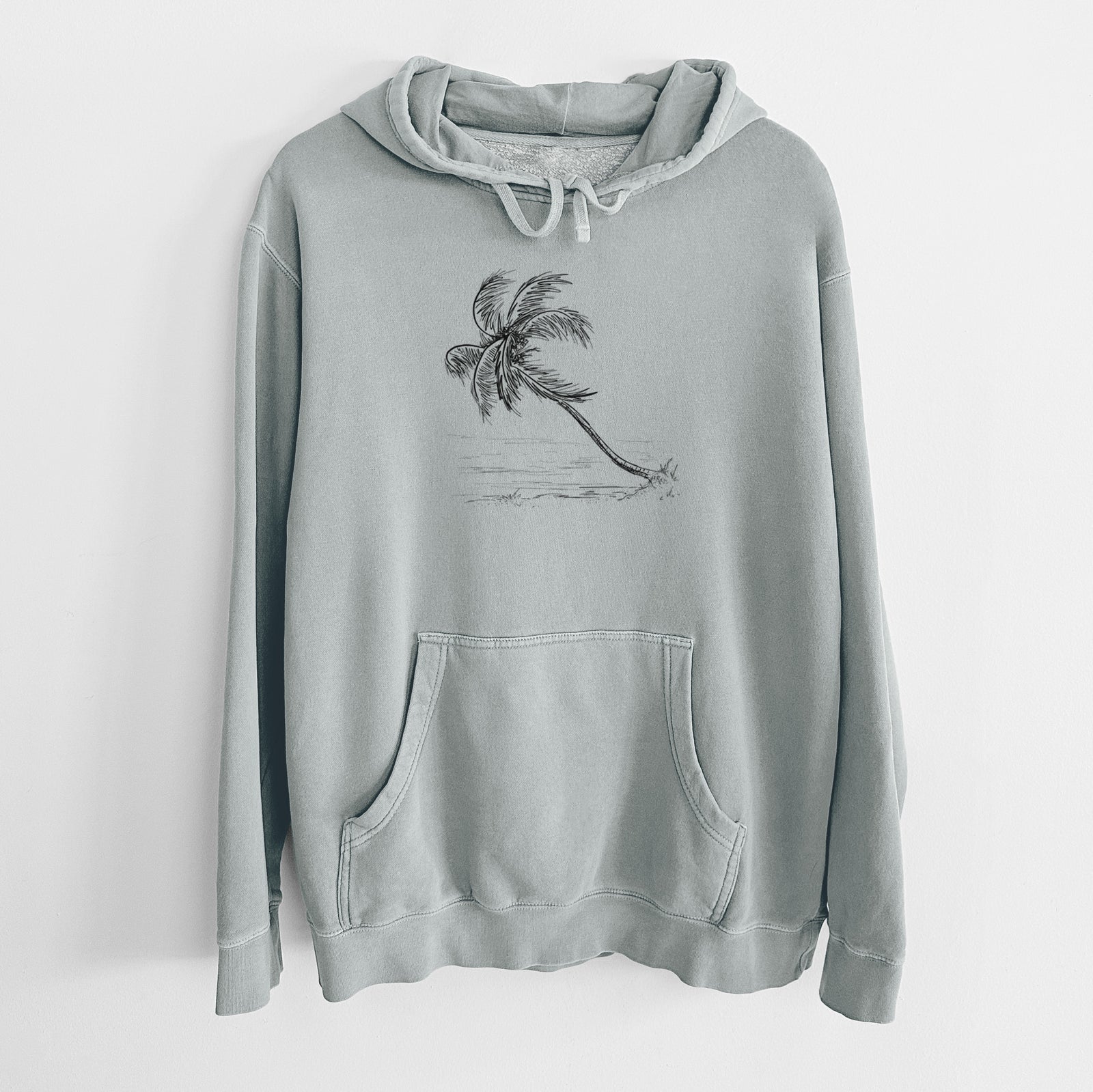 Sage green pigment dyed hoodie laid flat, printed with a black ink illustration of a coconut palm leaning over a sandy beach.