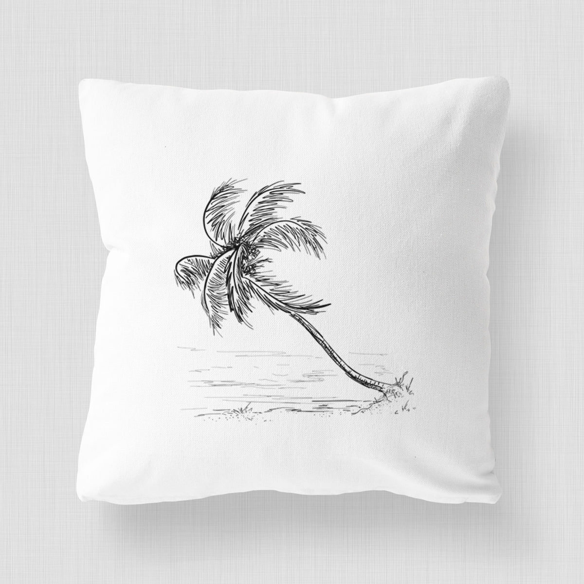 White pillow cover printed with a black ink illustration of a coconut palm leaning over a sandy beach.