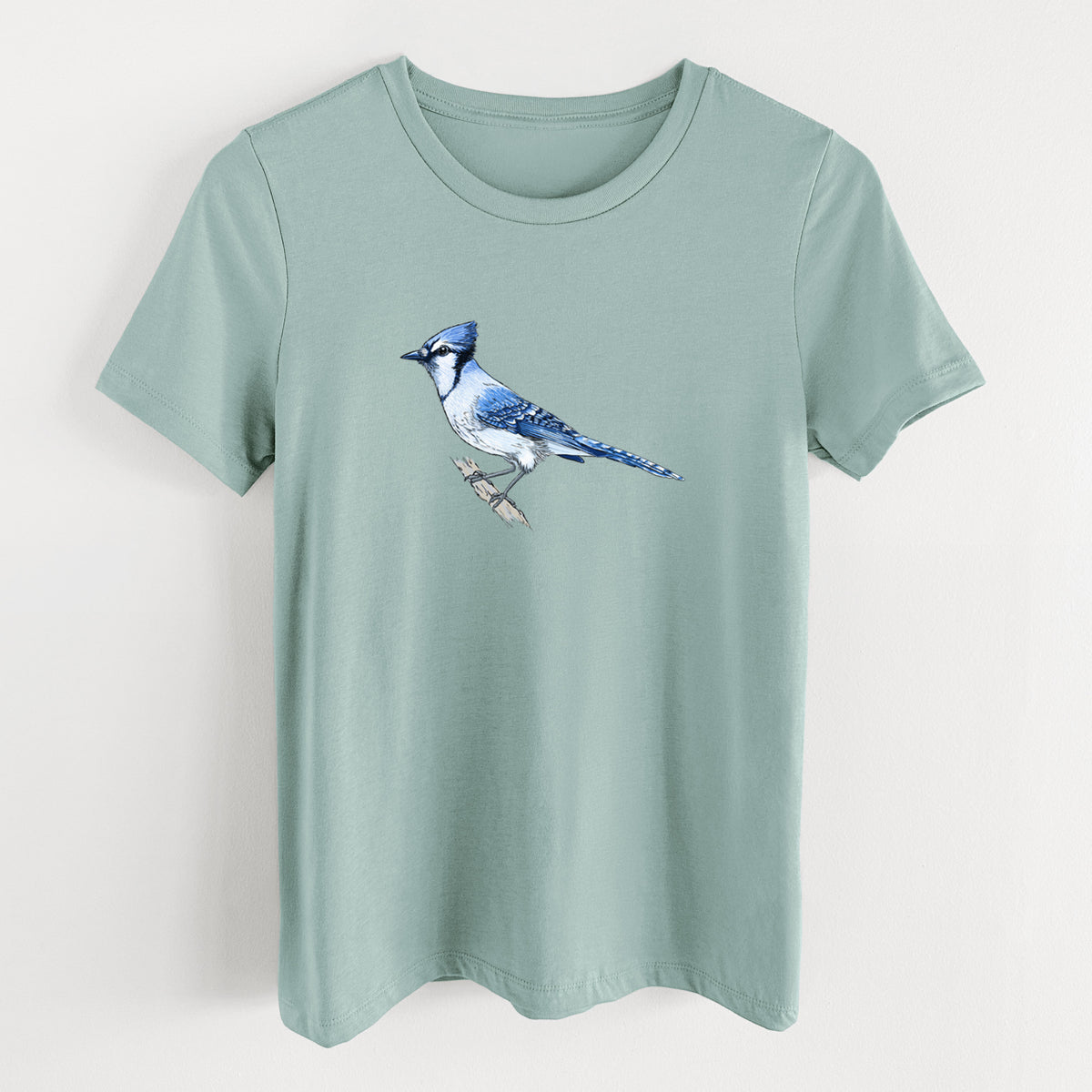 Dusty blue women's relaxed fit cotton t-shirt laid flat, printed with a full-color illustration of a blue jay perched on a branch.