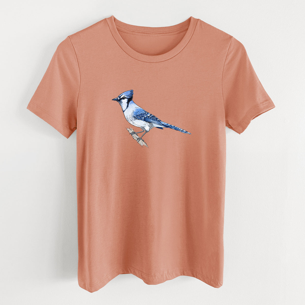 Terracotta orange women's relaxed fit cotton t-shirt laid flat, printed with a full-color illustration of a blue jay perched on a branch.