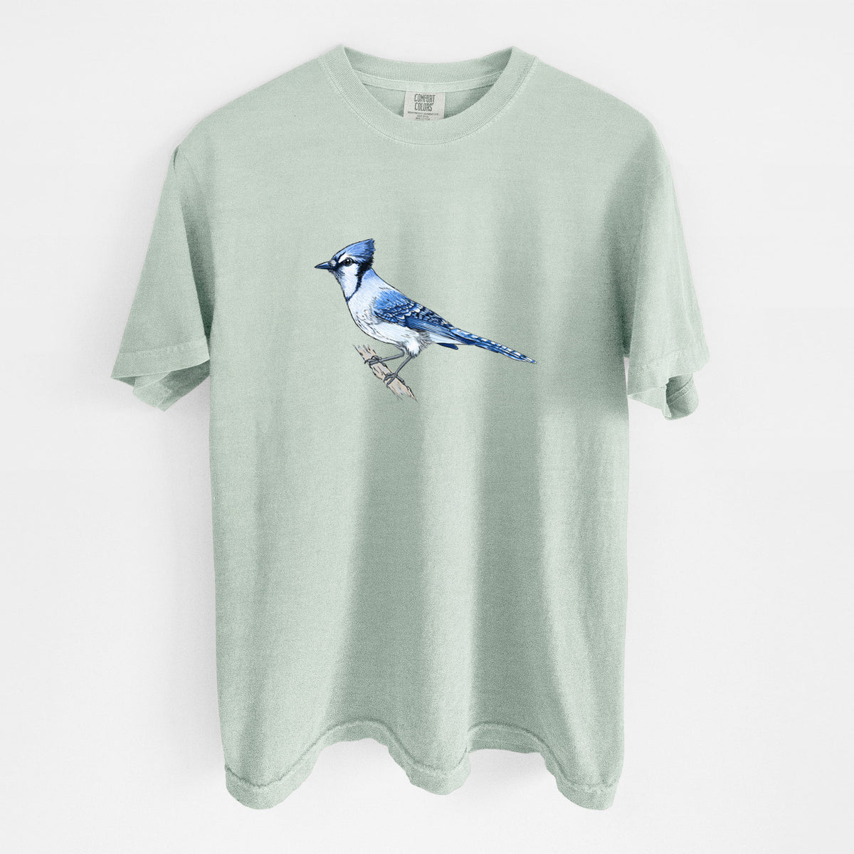 Bay green Comfort Colors t-shirt laid flat, printed with a full-color illustration of a blue jay perched on a branch.