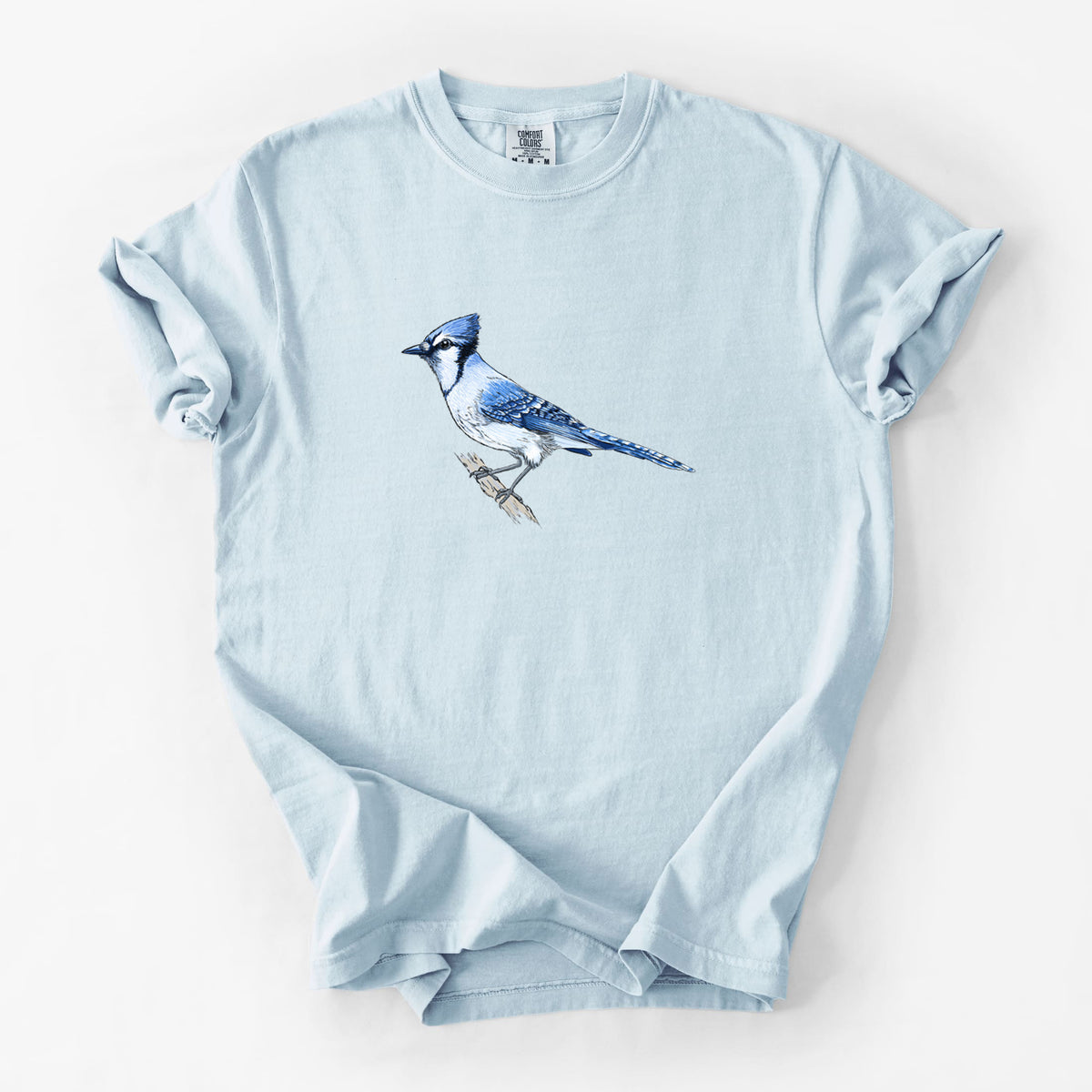 Chambray blue Comfort Colors t-shirt laid flat, printed with a full-color illustration of a blue jay perched on a branch.