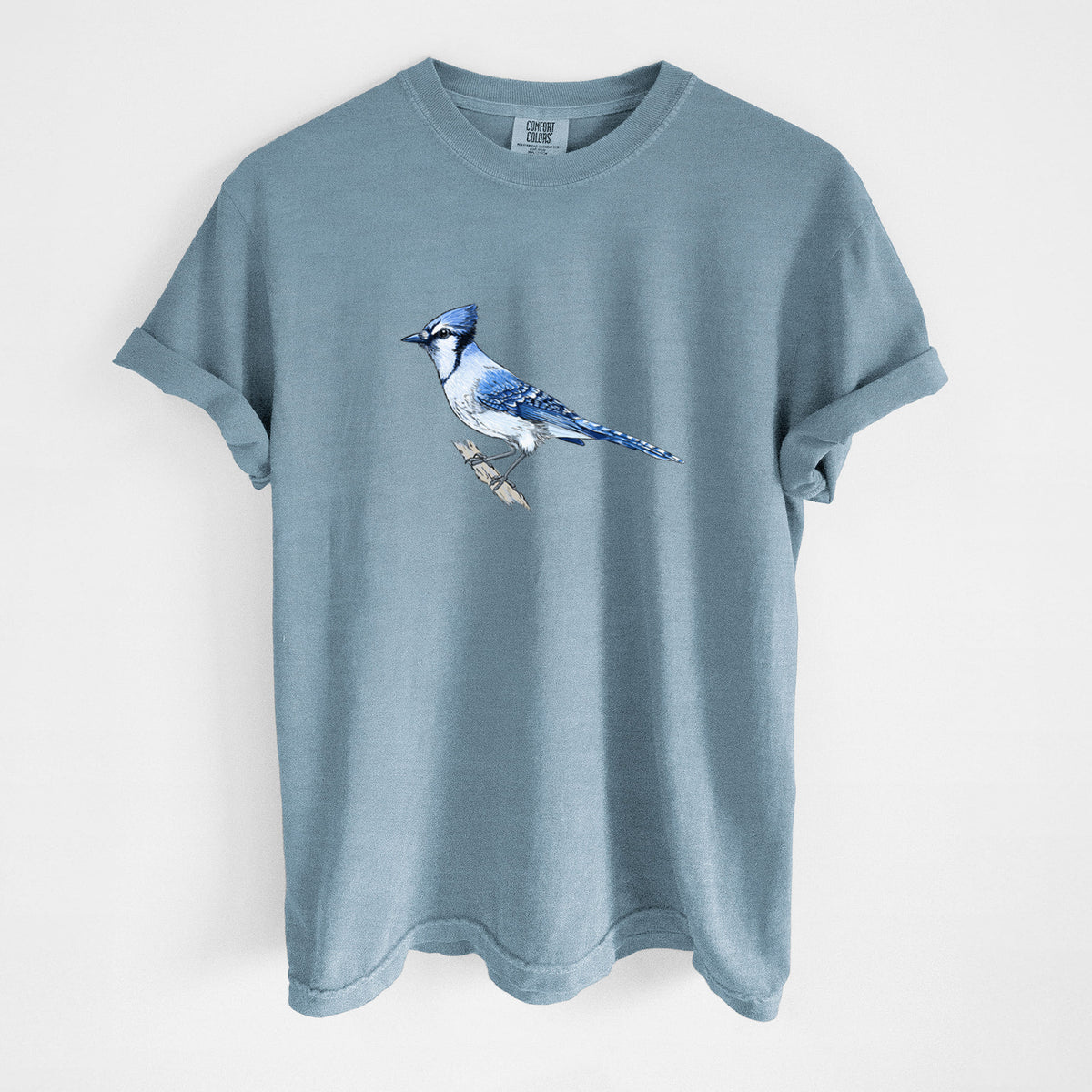 Steel blue Comfort Colors t-shirt laid flat, printed with a full-color illustration of a blue jay perched on a branch.