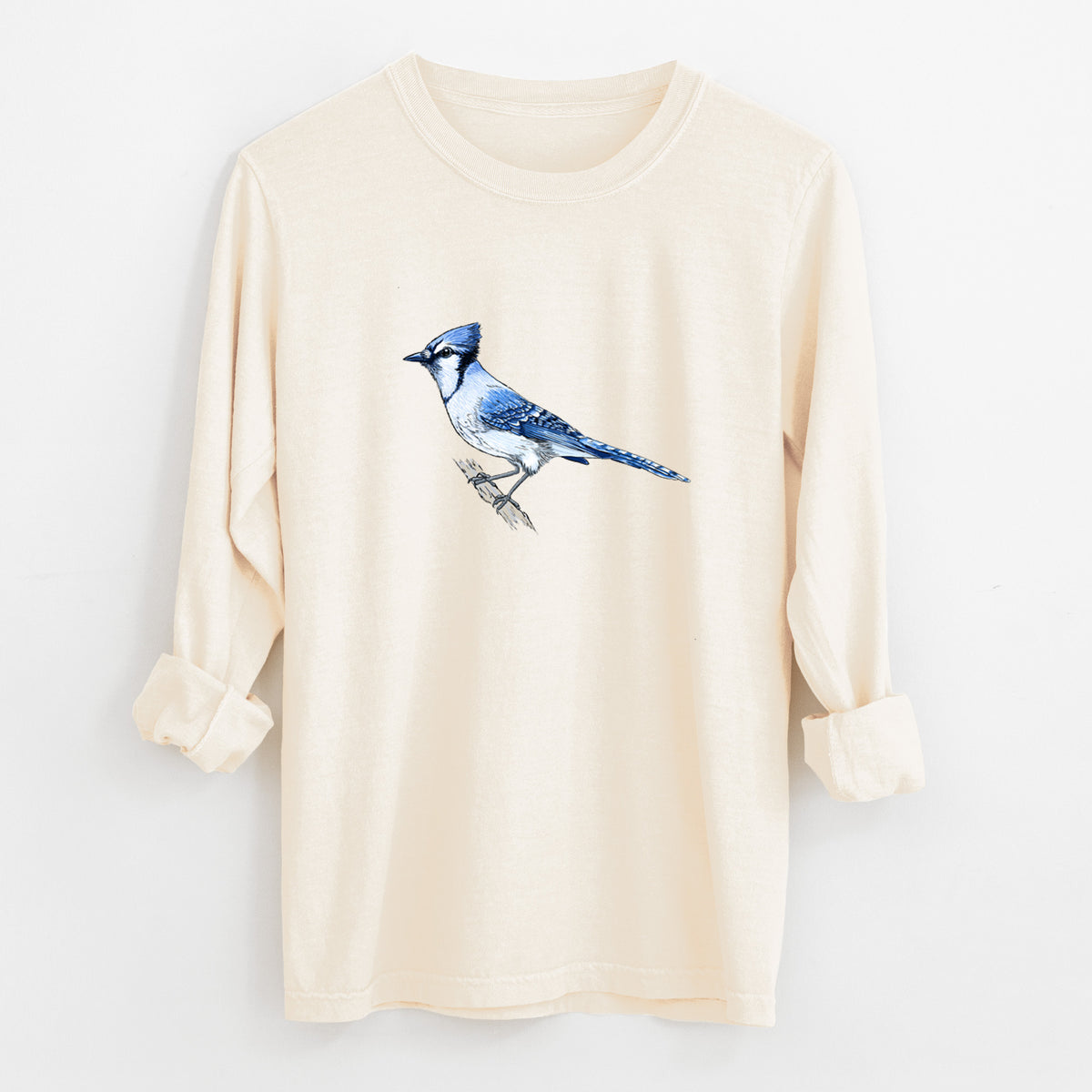Ivory Comfort Colors long sleeve shirt laid flat with the cuffs rolled, printed with a full-color illustration of a blue jay perched on a branch.