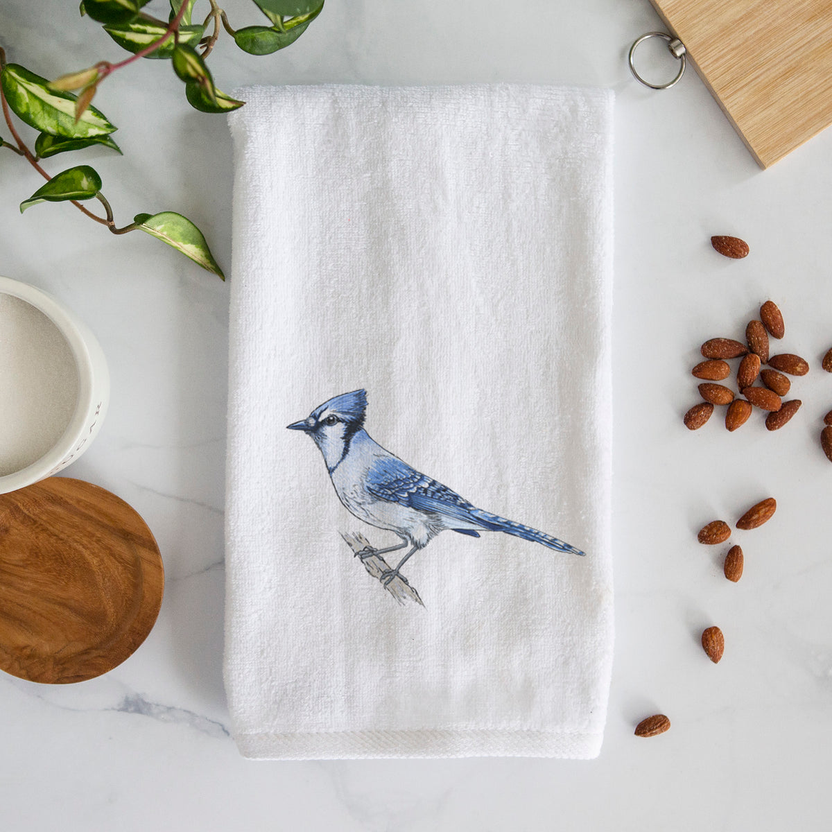 White hand towel printed with a full-color illustration of a blue jay perched on a branch.