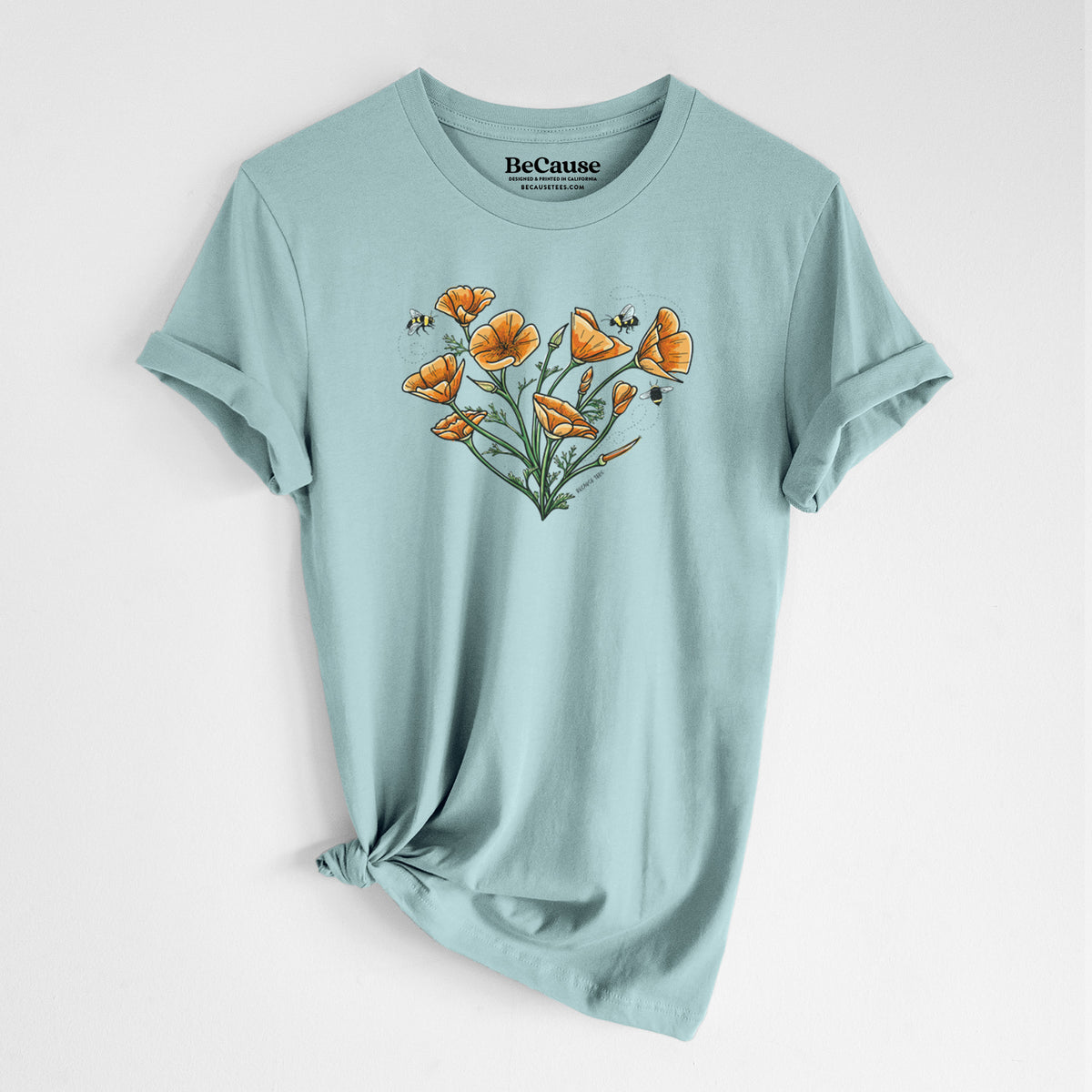 Dusty blue lightweight cotton t-shirt laid flat with the sleeves rolled, printed with a full-color bouquet of orange California poppies arranged in a heart shape, with small bees.